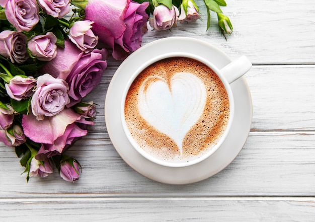 Tasse de café du matin et de belles fleurs roses sur fond clair, vue de dessus. Petit déjeuner confortable. Mise à plat