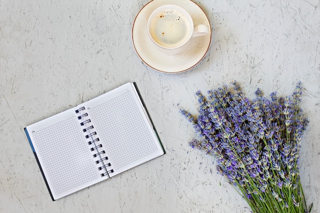 Tasse à café du matin, bloc-notes vide et fleurs de lavande violette sur fond gris