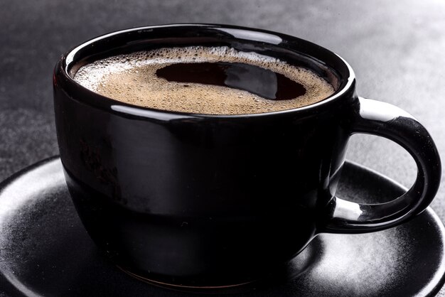 Une tasse de café du matin fraîchement parfumé pour bien démarrer la journée. Belle tasse de café avec du café sur une table sombre