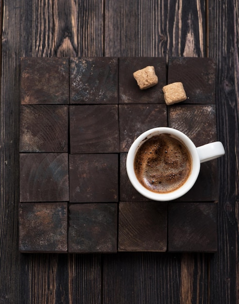 Tasse de café avec du sucre sur un fond en bois foncé