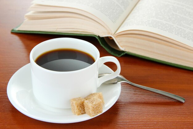 Tasse de café avec du sucre et livre sur fond de bois