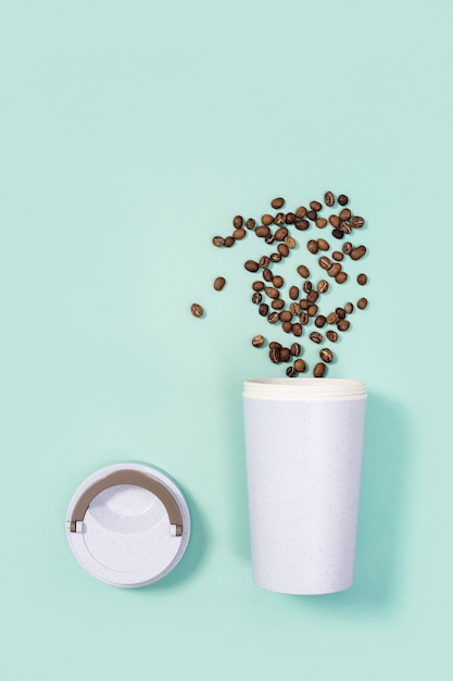 Tasse à café écologique réutilisable avec grains de café torréfiés.