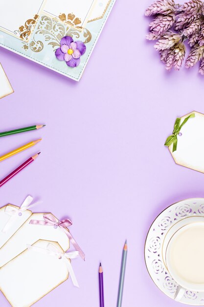 Tasse à café élégante, carnet de notes et feuilles de papier à plat. Fond féminin aux couleurs pastel. Vue de dessus