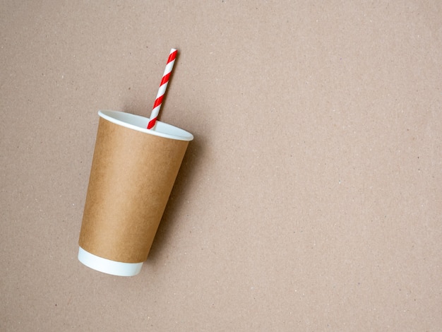 Tasse à café à emporter avec du papier paille blanche et rouge sur fond de papier craft. Le concept d'un monde sans plastique et d'une planète propre. Espace pour le texte. Zero gaspillage. Mise à plat, vue de dessus