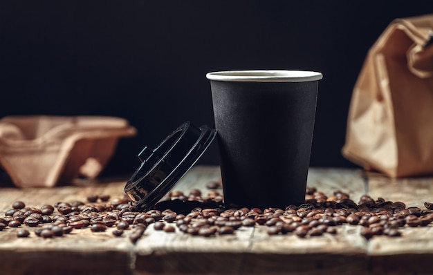 Tasse de café à emporter et grains de café sur fond de bois