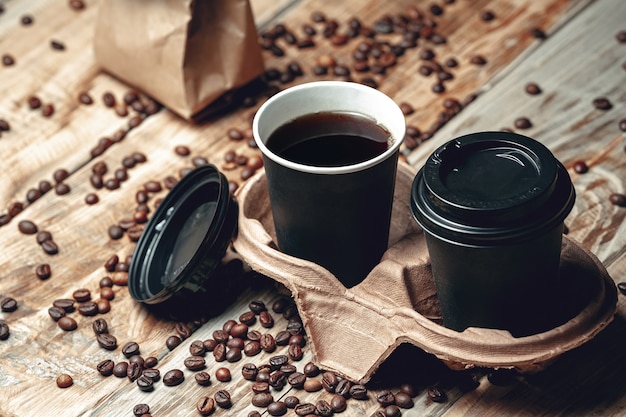 Tasse de café à emporter et grains de café sur table en bois