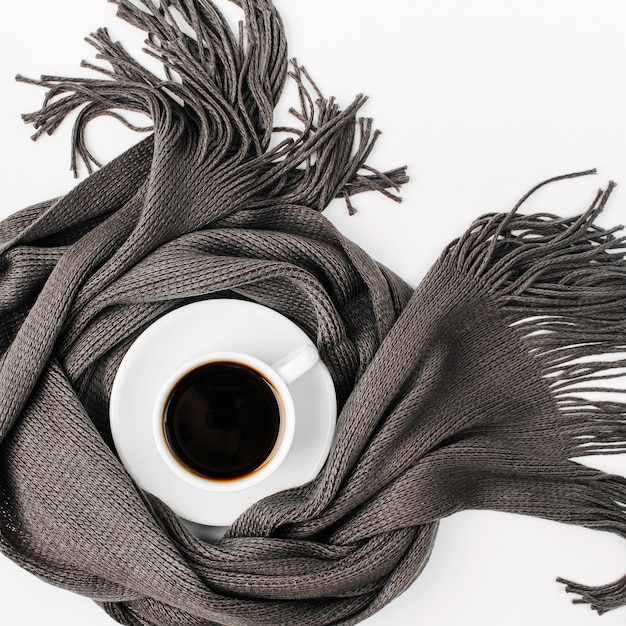 Une tasse de café enveloppée dans un foulard. Concept d'automne ou d'hiver. mise à plat, vue de dessus
