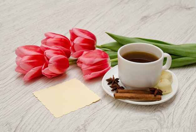 Tasse à café avec des épices, note propre, tulipes roses sur un bois