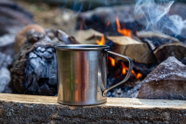 Une tasse de café est posée sur une bûche à côté d'un foyer.