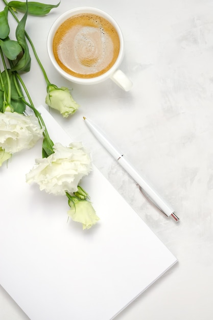 Tasse de café, eustoma, cahier et stylo sur fond de béton. Vue de dessus à plat au-dessus. Copier l'arrière-plan de l'espace