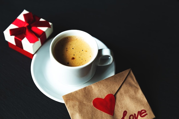 Tasse de café expresso avec cadeau et saint valentin. Fond noir, mise au point sélective.