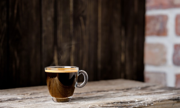 Tasse avec café expresso disposé sur une table en bois sombre. Gros plan, mise au point sélective, espace copie