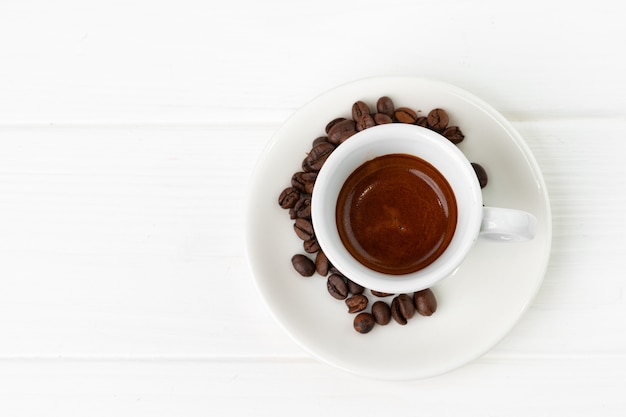 Tasse de café expresso et grains de café sur une surface blanche