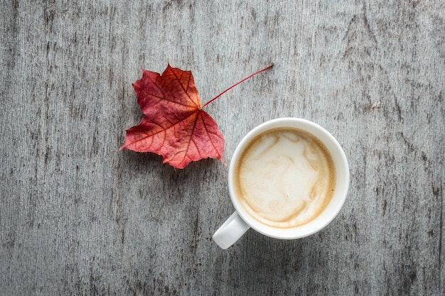 Une tasse de café et de feuilles d&#39;automne sur une table en bois