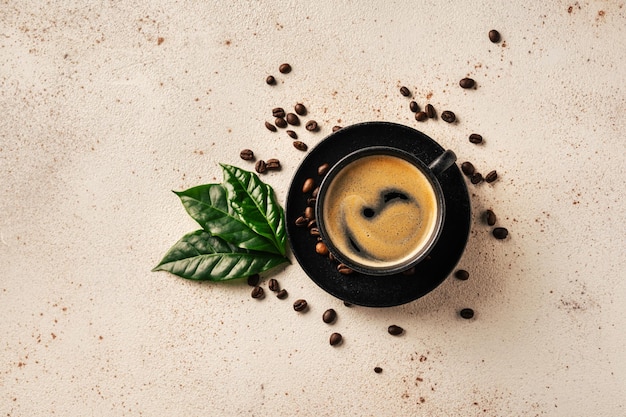 Une tasse de café avec des feuilles vertes et des haricots sur un fond clair vue supérieure Café et bar concept d'art barista