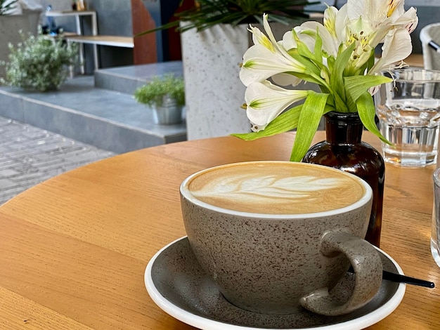 Une tasse de café avec une fleur en arrière-plan