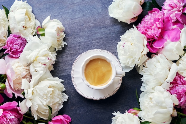 Une tasse de café et de fleurs de pivoine sur bois sombre. Vue de dessus