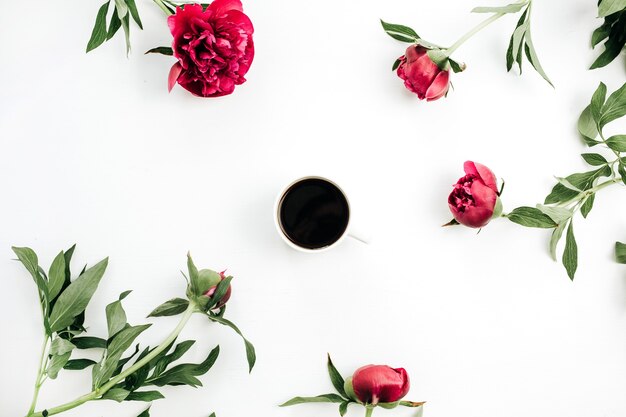 Tasse à café et fleurs de pivoines roses sur une surface blanche