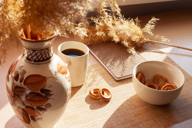 Une Tasse De Café, Fleurs Séchées, Barankis, Bloc-notes Sur Table En Bois. Marron Et Blanc.