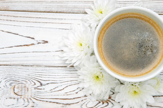 Tasse de café et de fleurs sur une table en bois clair