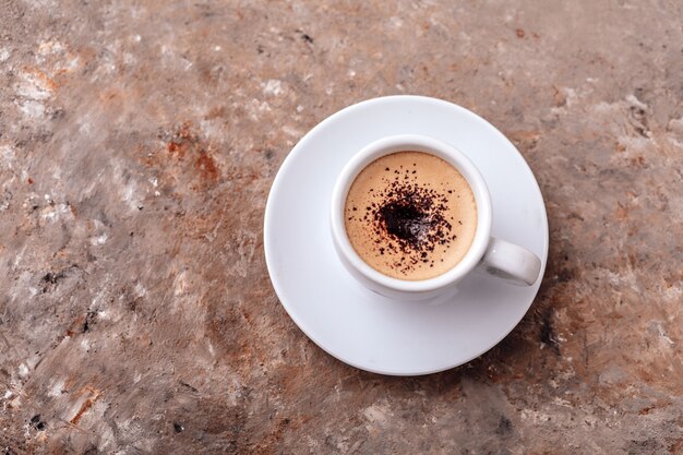 Tasse de café sur fond gris Une seule tasse de café avec de la crème et des pépites de chocolat