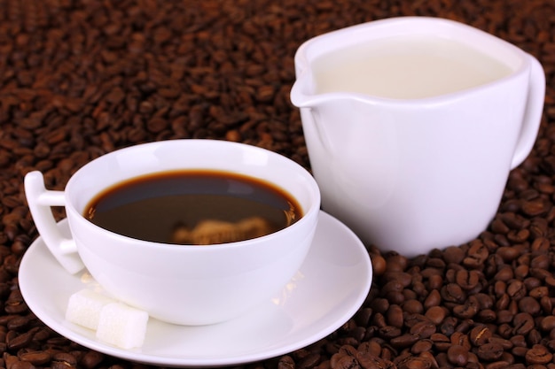 Une tasse de café fort et de crème sucrée sur les grains de café en gros plan
