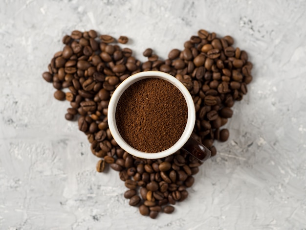 Une tasse de café fraîchement moulu sur la table avec des grains de café en forme de coeur