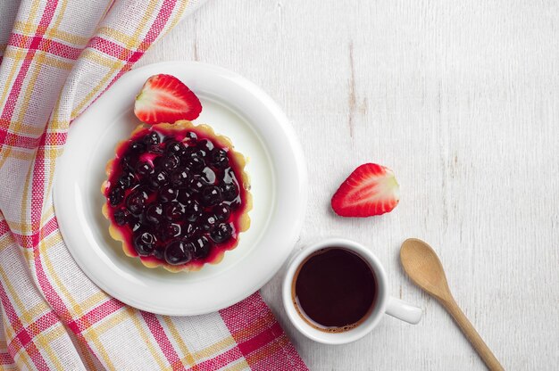 Tasse à café, gâteau aux cassis et fraise sur table, vue de dessus