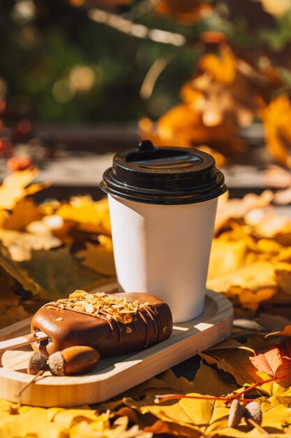 Une tasse de café et un gâteau sur un plateau en bois à l'extérieur contre les feuilles jaunes