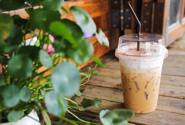 Tasse de café glacé sur le vieux bureau en bois avec feuille verte au premier plan
