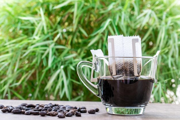 Tasse à café goutte à goutte sur une table en bois avec des grains de café