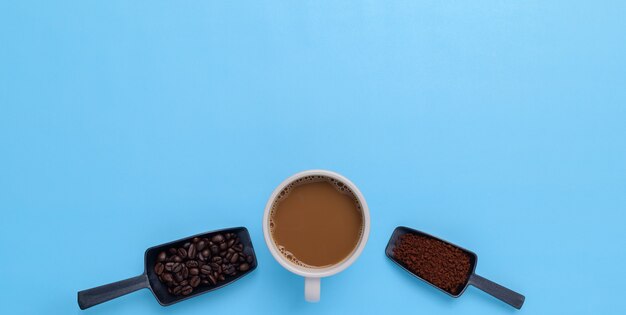 Tasse à café, grains de café, café moulu sur fond bleu