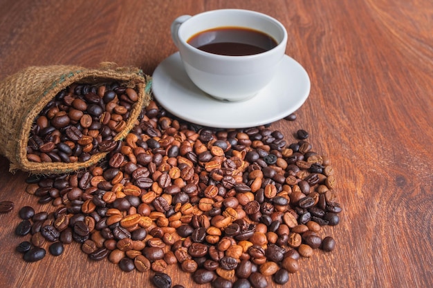 Tasse de café et de grains de café dans un sac sur fond marron