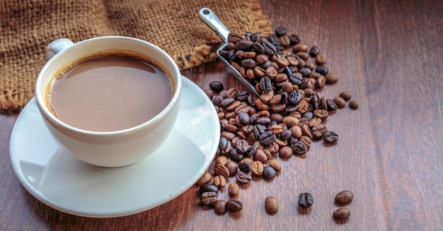 Tasse de café et grains de café dans un sac sur la vue de dessus de fond marron