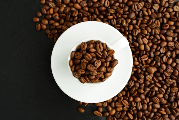 Tasse à café en grains de café dans une tasse de café blanche sur fond noir