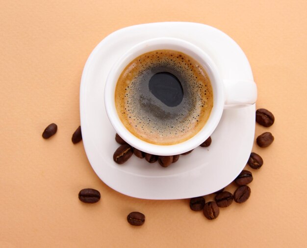 Tasse de café avec des grains de café sur fond beige