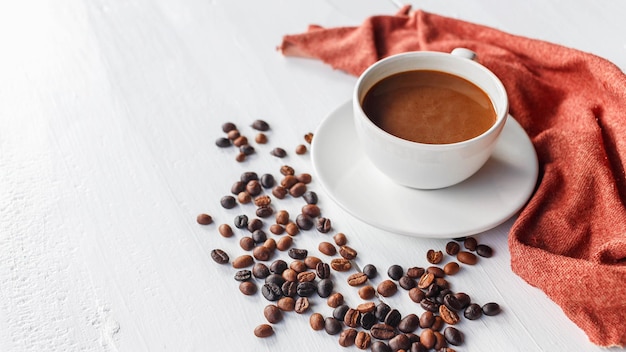 Tasse à café et grains de café sur fond de bois blanc