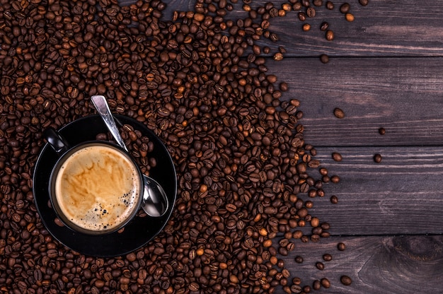 Tasse à café et grains de café sur un fond en bois noir