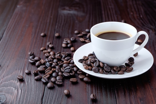 Tasse à café et grains de café sur fond en bois.