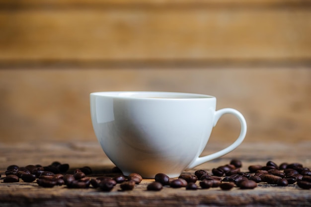 Une tasse de café avec des grains de café sur fond de bois