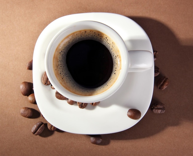 Tasse de café avec des grains de café sur fond marron