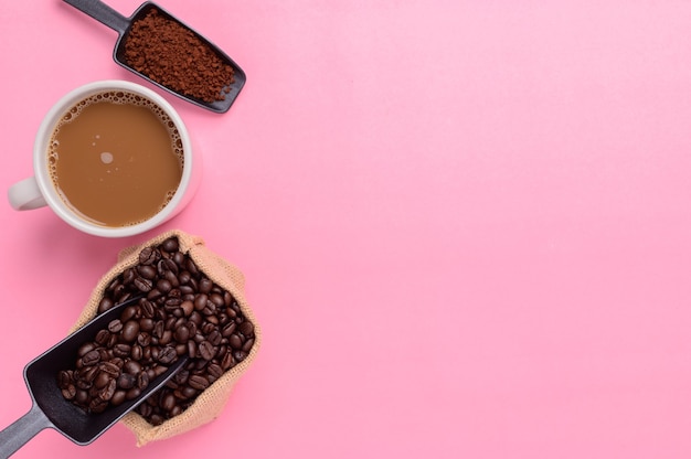 Tasse à café et grains de café sur fond rose