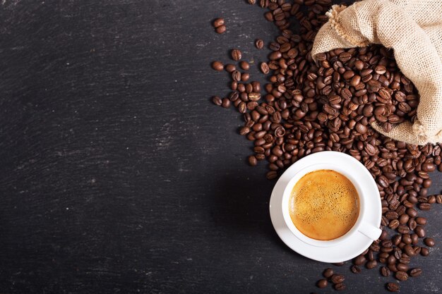 Tasse de café et grains de café sur fond sombre