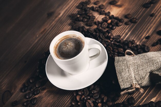 Tasse à café et grains de café sur fond de tissu de sac.