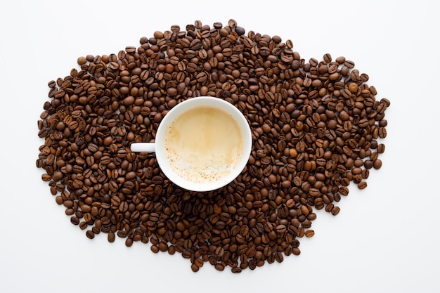 Tasse de café sur les grains de café sur un mur blanc