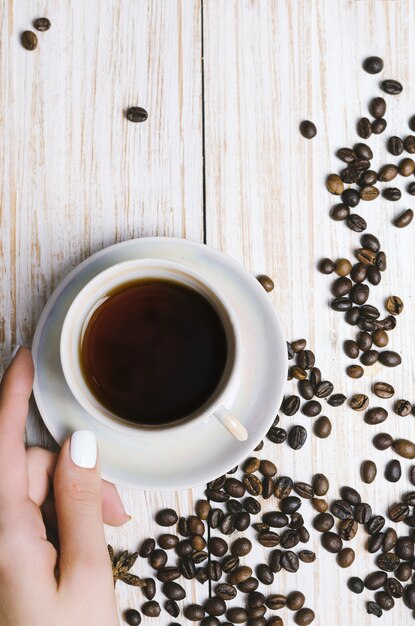 Tasse de café et grains de café sur planche de bois.