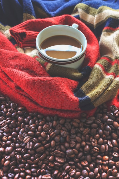 Tasse de café et grains de café avec un pull rouge.