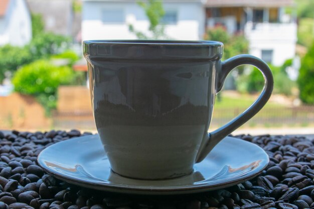 Une tasse de café sur les grains de café rôtis près de la fenêtre