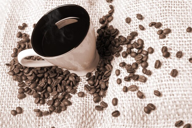 Tasse de café avec des grains de café sur la toile de jute