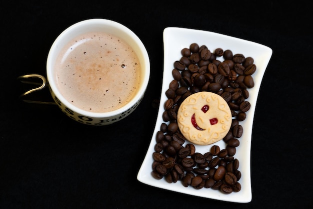 tasse de café en grains de café et vue de dessus de biscuit souriant